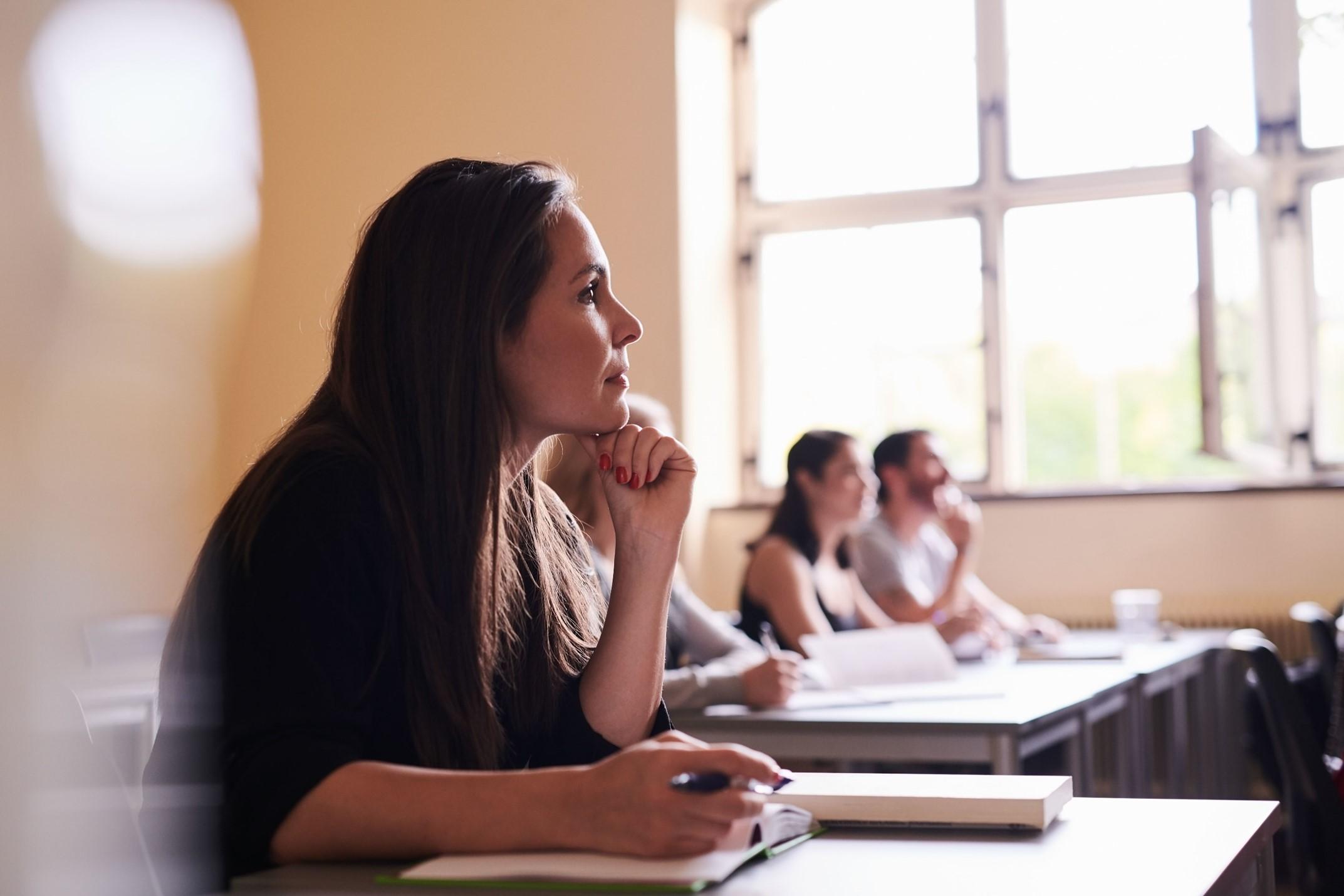 A woman looking intently forward while holding a notebook and pen