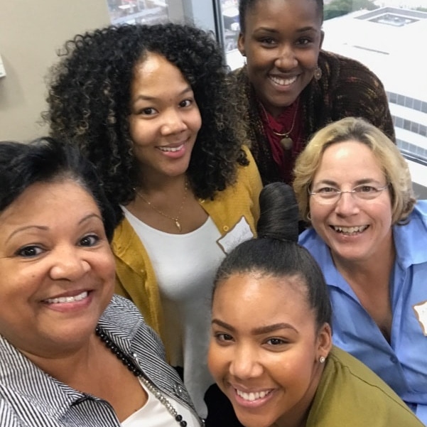 Four women in professional attire posing together at a WID Greater Hampton Roads networking event
