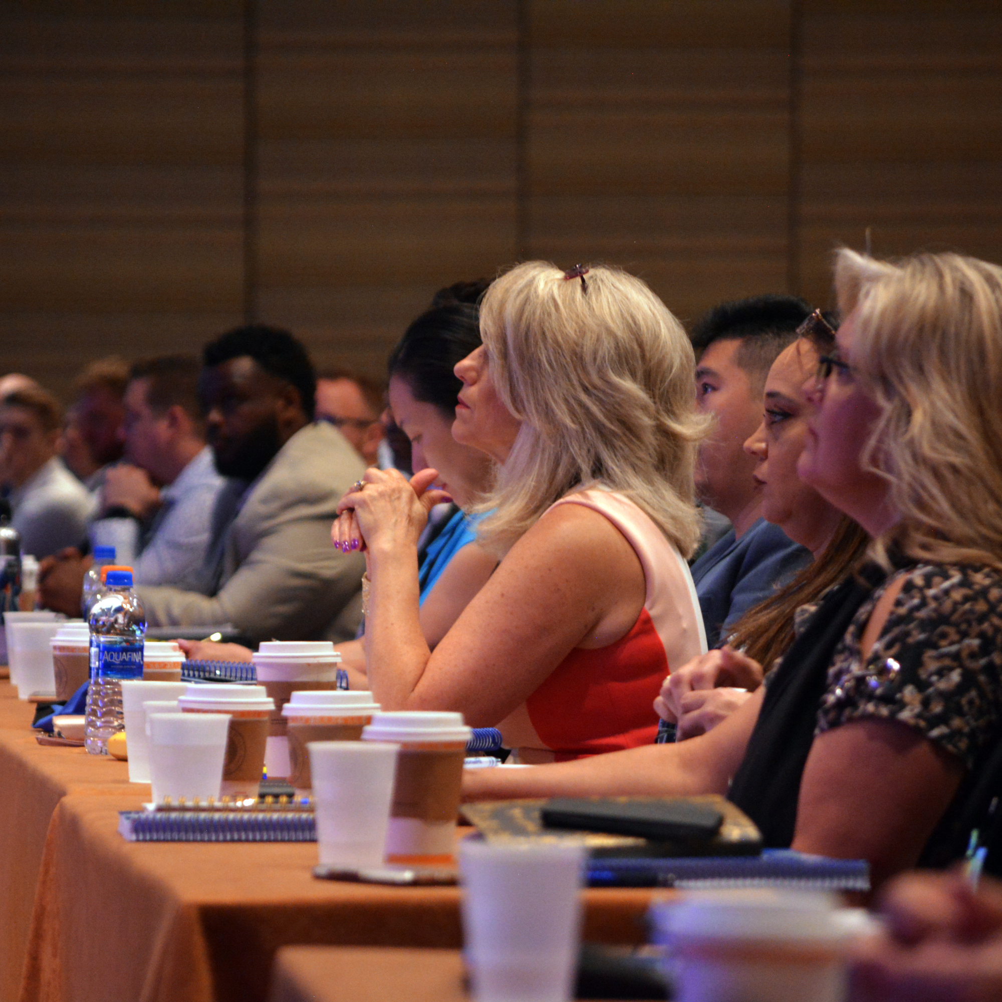 Women and men seated at a conference looking towards the speaker
